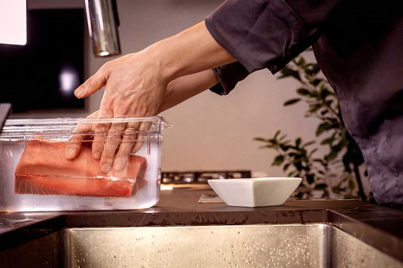 Hands placing the tuna in the salted-water bath